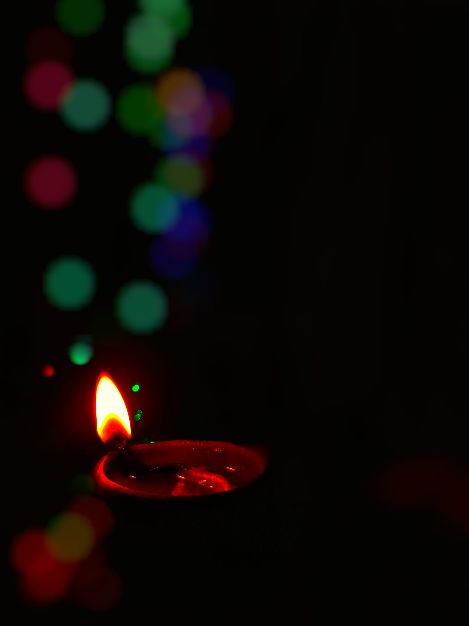 Una vela encendida en la oscuridad con un fondo borroso (día, diwali, festival, saludos, feliz)