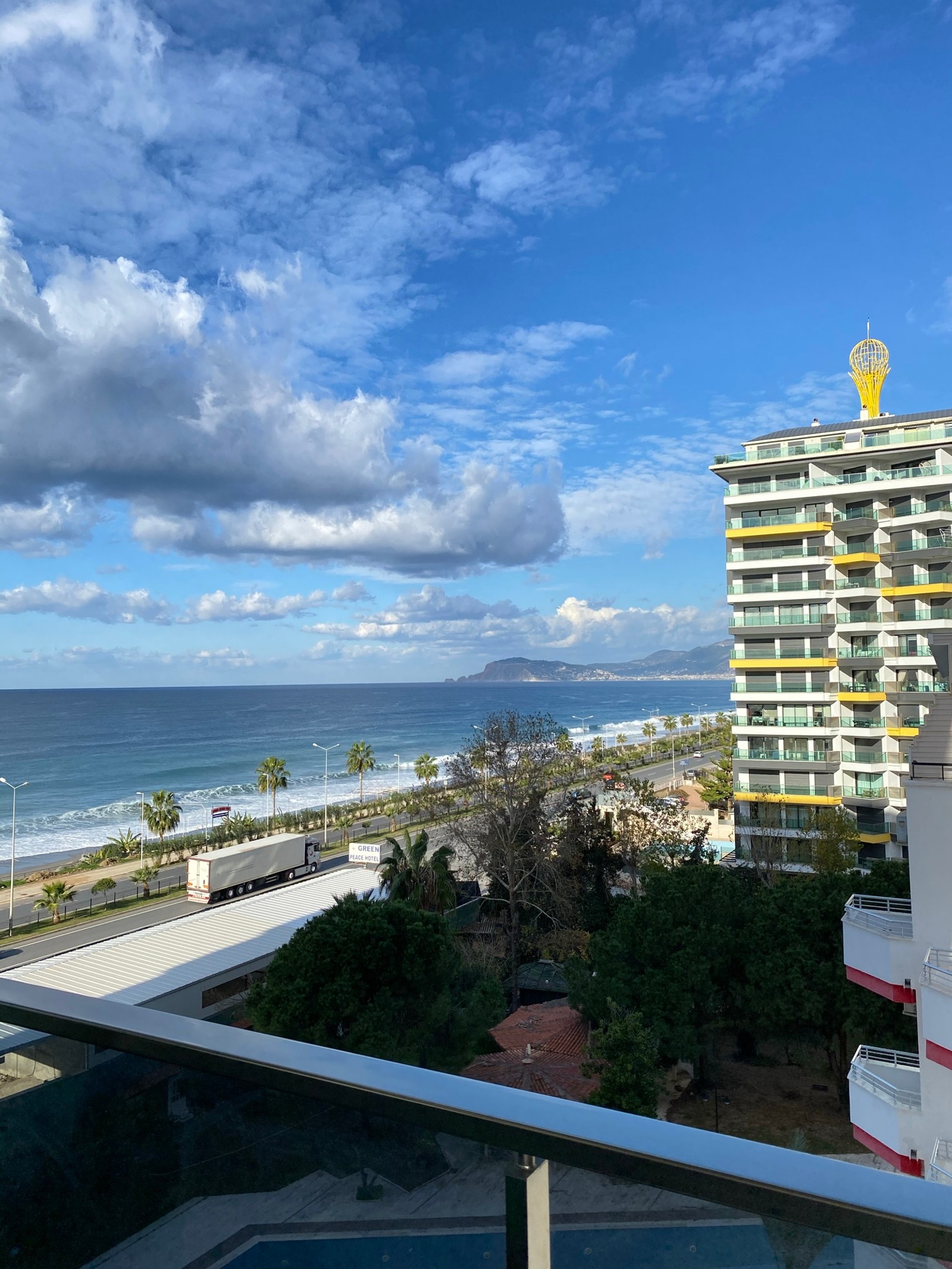 Há uma vista de uma praia a partir de uma varanda de um edifício (condomínio, imóveis, propriedade, nuvem, edifício)