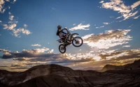 Intérprete de acrobacias de motocross freestyle volando contra un dramático atardecer