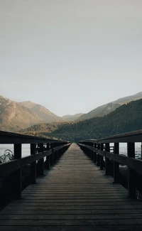 Tranquil Pier Stretching into Serene Mountain Reflections