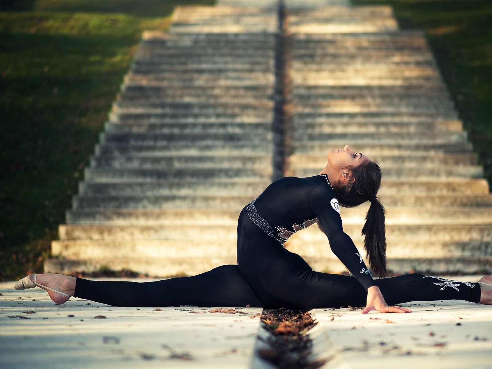 Mulher árabe em um traje preto e branco fazendo uma pose de yoga (ginástica, sentado, aptidão física, ginástica rítmica, luz)