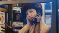 Chaeyoung in a phone booth, radiating confidence with a playful expression, set against a vibrant, night-time backdrop.