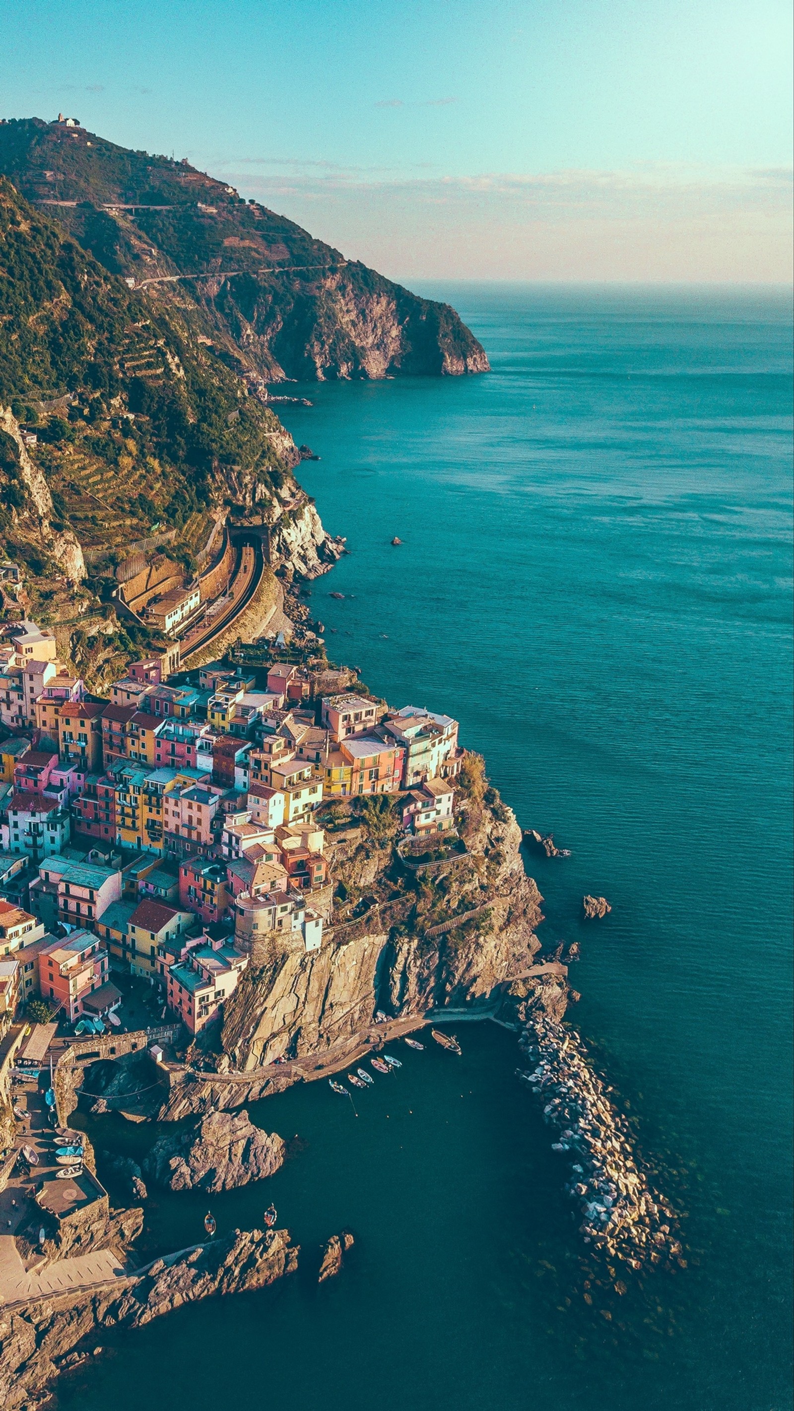 Vista aérea de un pequeño pueblo en un acantilado con vista al océano (manarola, naturaleza, mar, parque, agua)