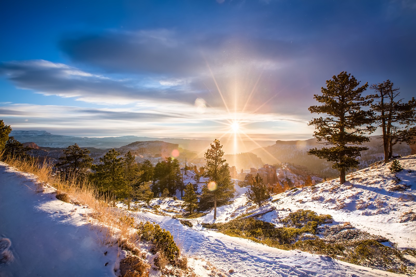 Vista de uma montanha nevada com o sol se pondo (neve, inverno, natureza, árvore, nuvem)