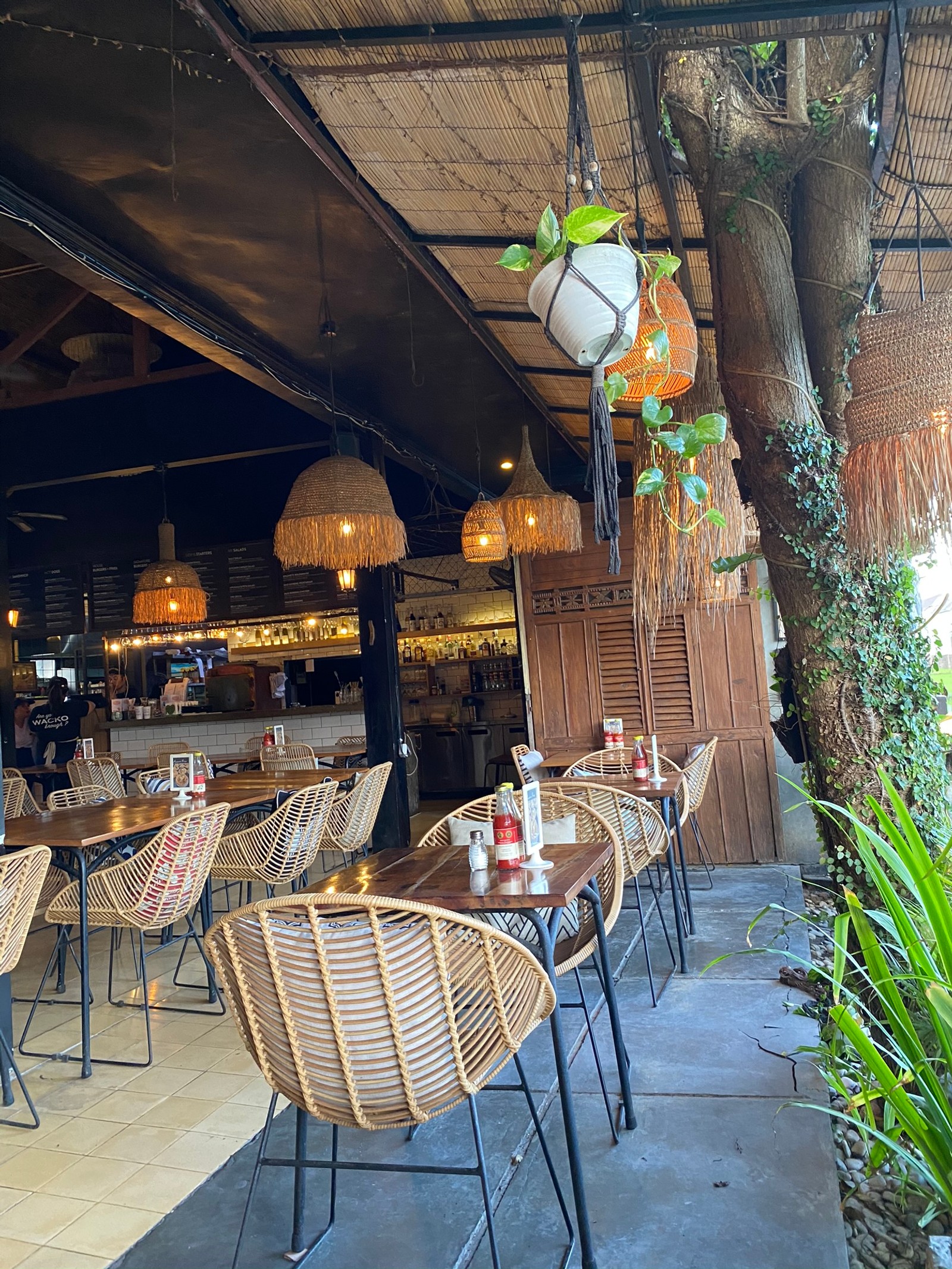 Es gibt viele stühle und tische in einem restaurant mit einem baum (tisch, beleuchtung, möbel, fleisch, lichtarmatur)