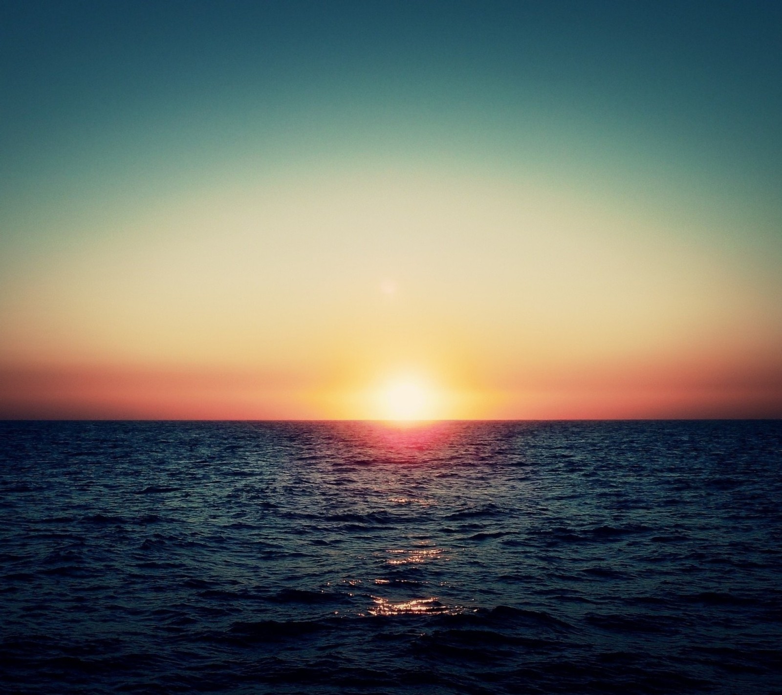 Vue panoramique d'un coucher de soleil sur l'océan avec un bateau au loin (paysage, ciel, soleil)