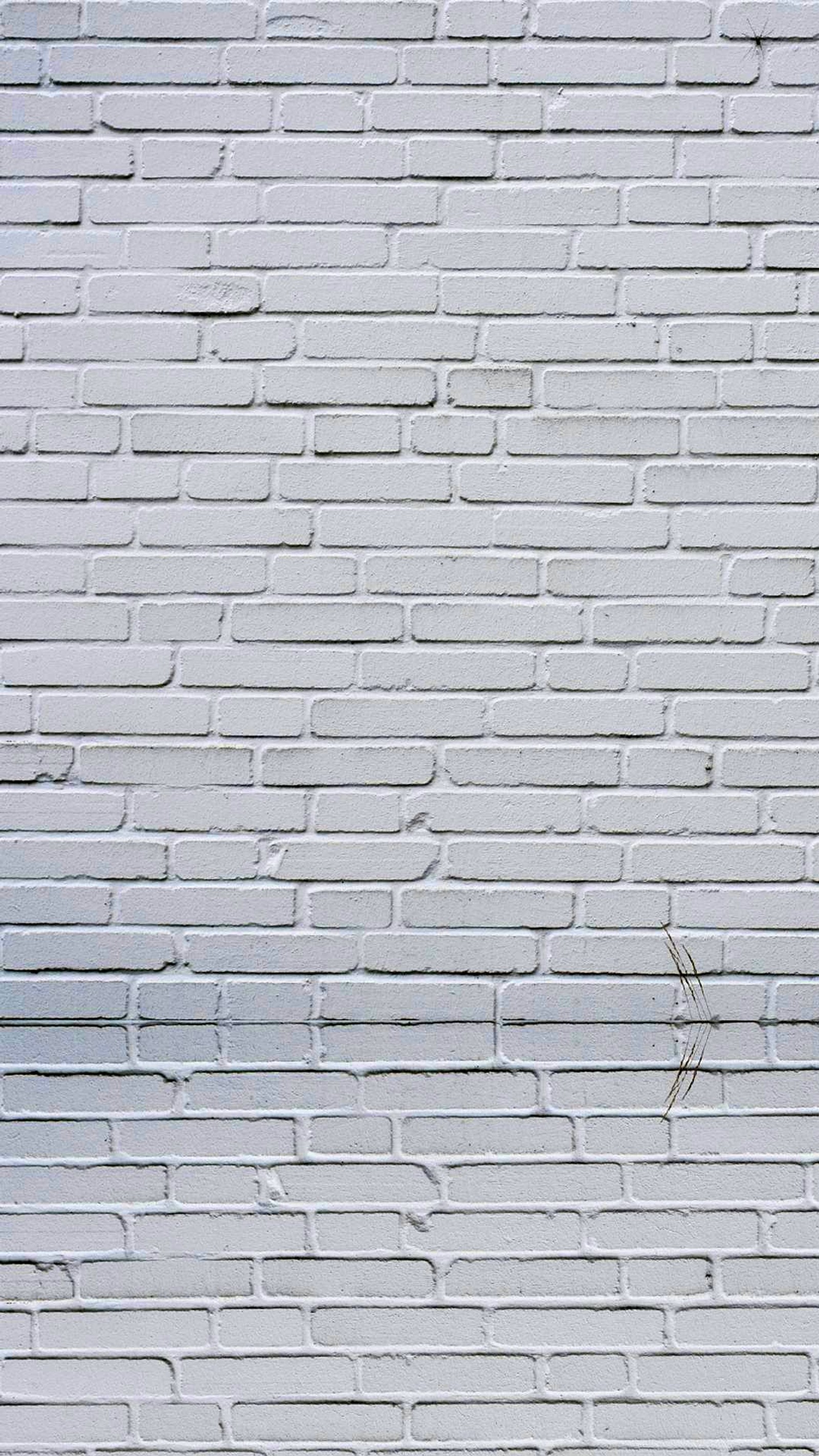 Un hidrante contra incendios en una pared de ladrillo con un fondo blanco (ladrillo, pared blanca)