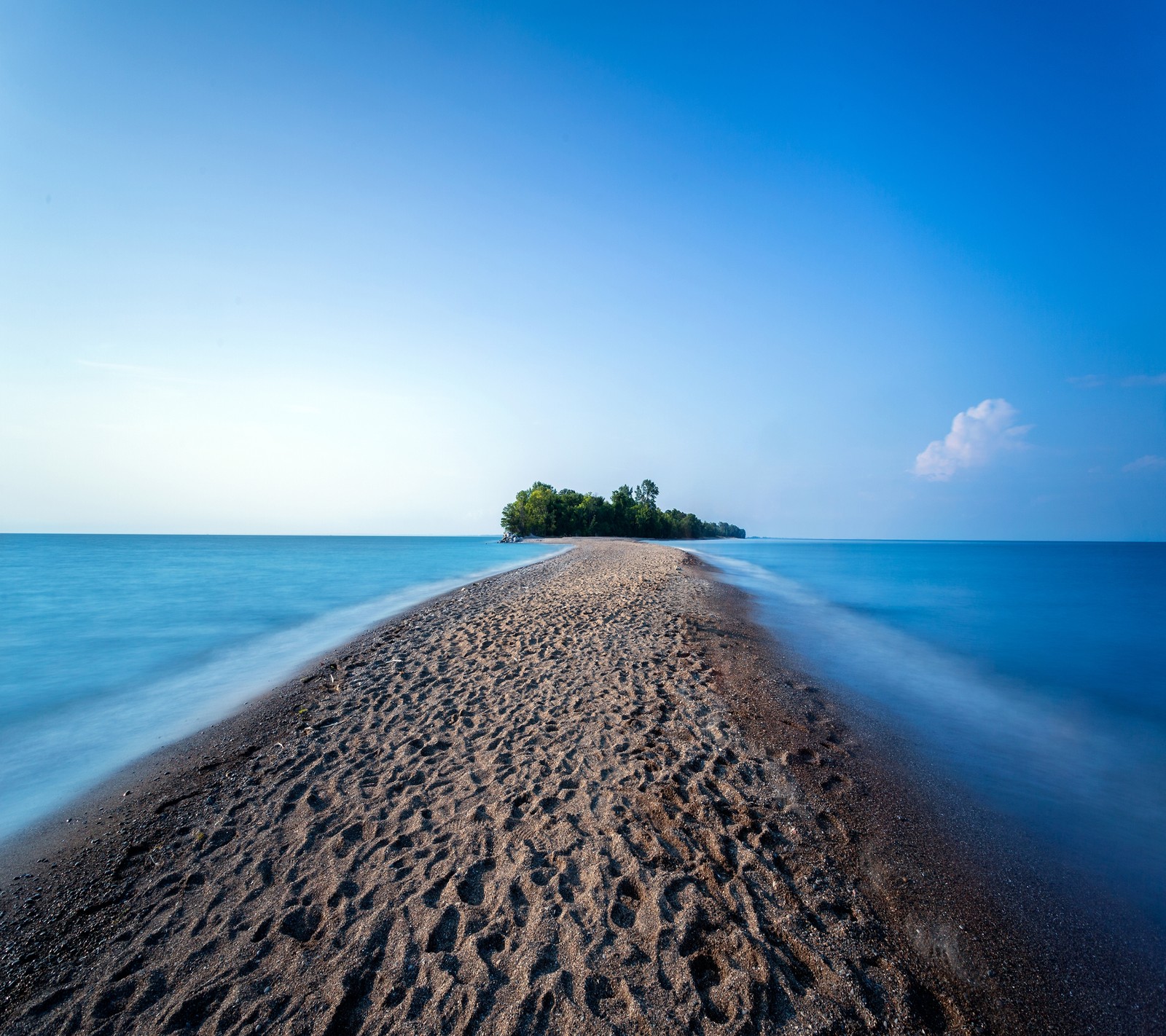 Vue aérienne d'une plage de sable avec une petite île au loin (plage, île, océan, paradis, mer)