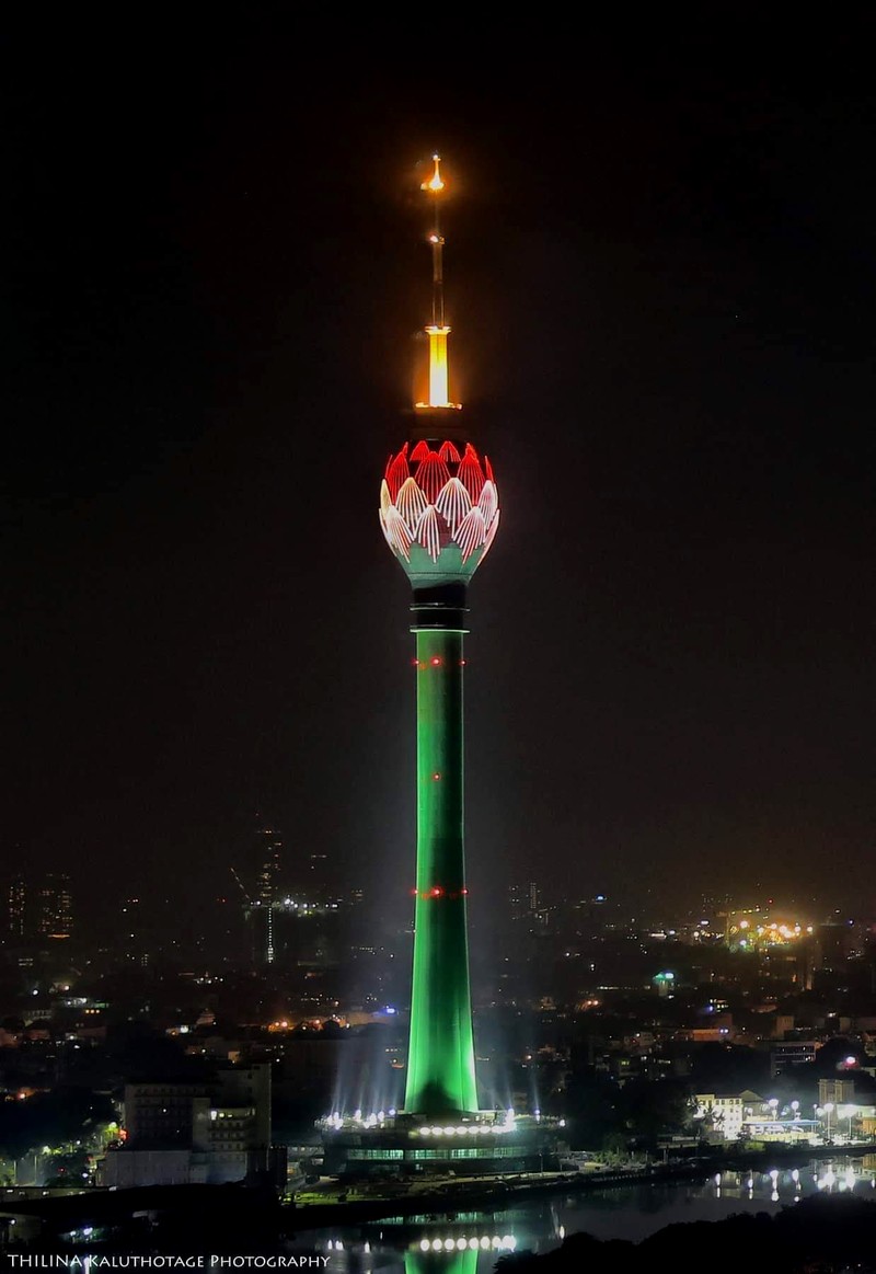 Vista artística de una torre alta con una flor roja y verde en la parte superior (faro, sri lanka, torre de loto, colombo, negro)