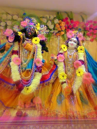 Krishna y Radha adornados con flores en una exhibición divina.