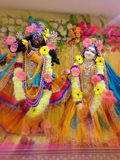 Krishna e Radha adornados com flores em uma exibição divina.