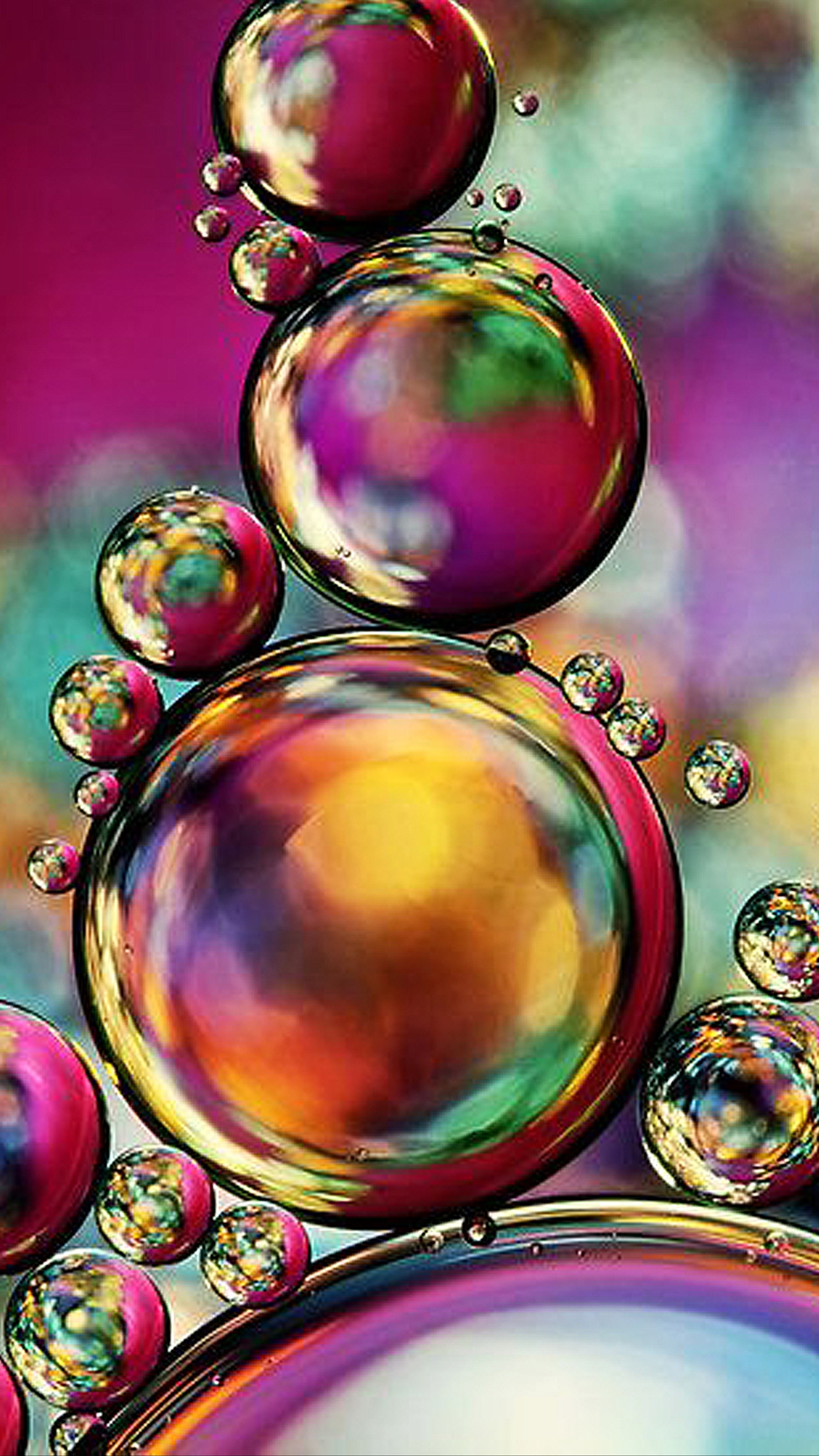 A close up of a bunch of bubbles floating in a water (bubble, color, green, pink, red)