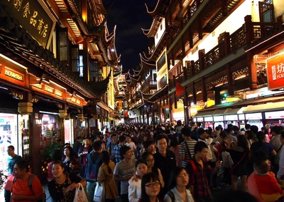 Escena vibrante de mercado nocturno en Shanghái, bulliciosa con multitudes y escaparates iluminados.