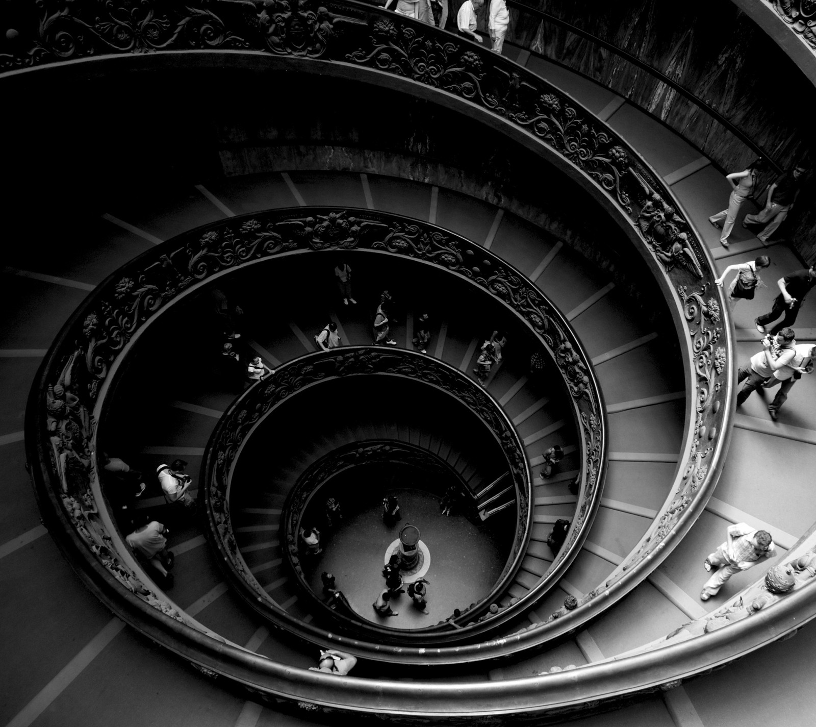 Escalier en colimaçon avec des gens descendant dans un bâtiment (bw, de, spirale, escaliers, the)