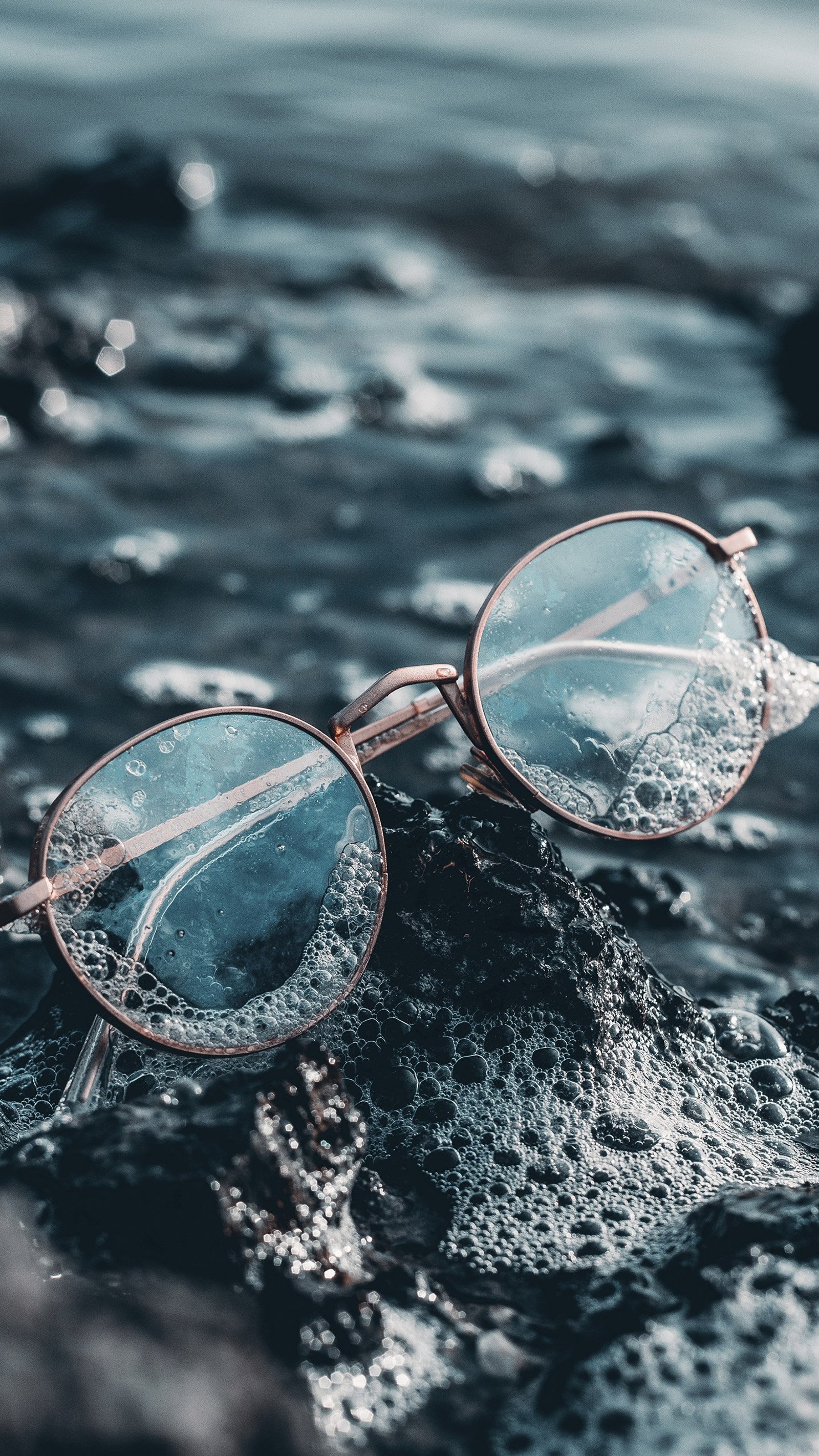 Sunglasses on a rock in the water with a blue background (glasses, sunglasses, aesthetics, water, water resources)