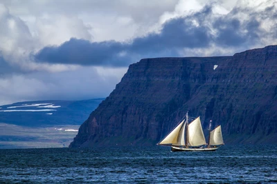 Sailboat Gliding Across a Serene Lake with Majestic Mountains in the Background