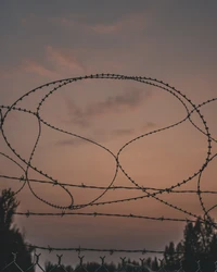 Silhueta de arame farpado contra um céu ao entardecer