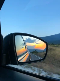 Reflet du coucher de soleil dans le rétroviseur latéral de l'automobile