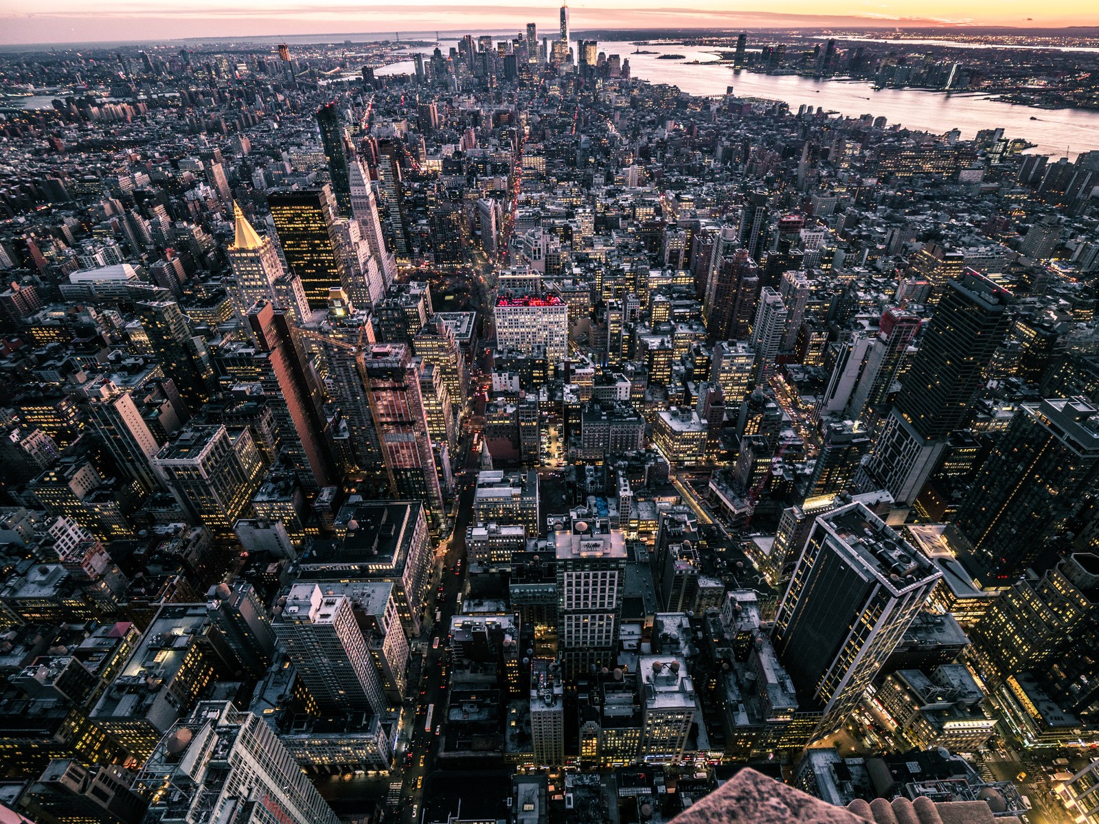 Una vista de una ciudad al atardecer desde la cima de un rascacielos (nueva york, new york city, empire state building, ciudad, paisaje urbano)