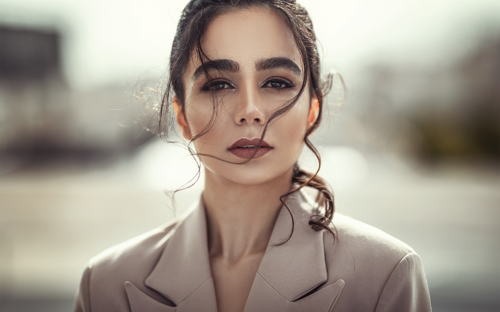 Une femme arabe avec un chignon décoiffé dans un costume et une veste. (visage, cheveux, lèvre, sourcil, expression faciale)