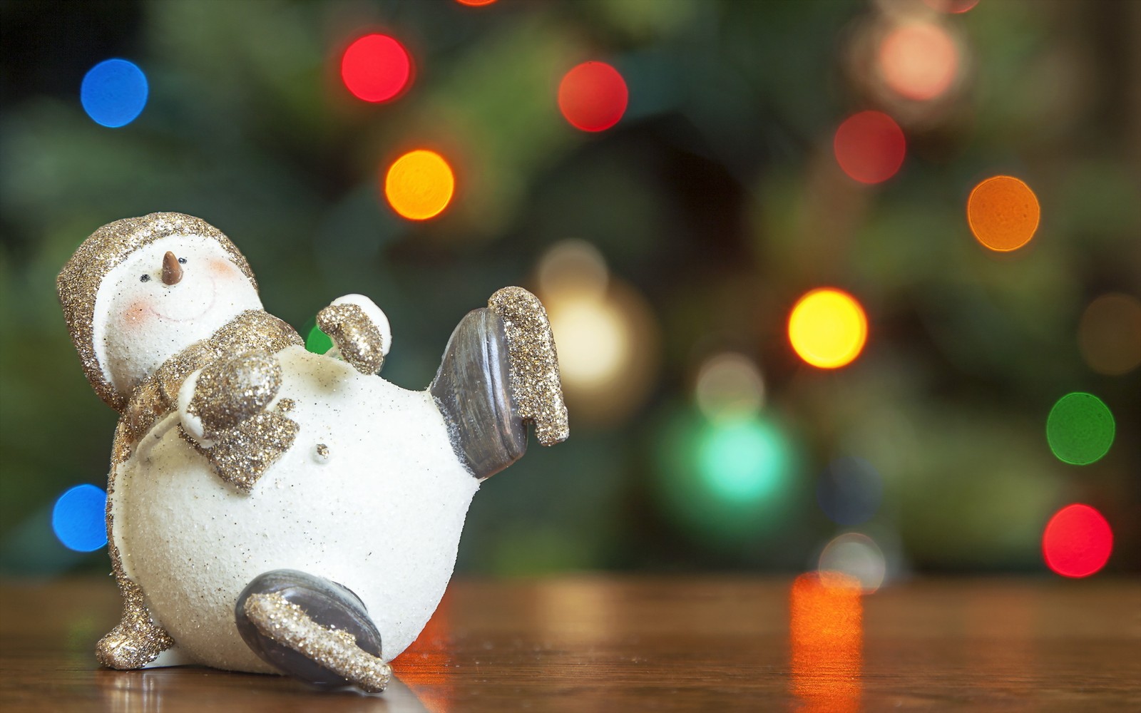 Eine schneemannfigur sitzt auf einem tisch mit einem weihnachtsbaum im hintergrund (weihnachtstag, schneemann, weihnachtsornament, baum, weihnachten)