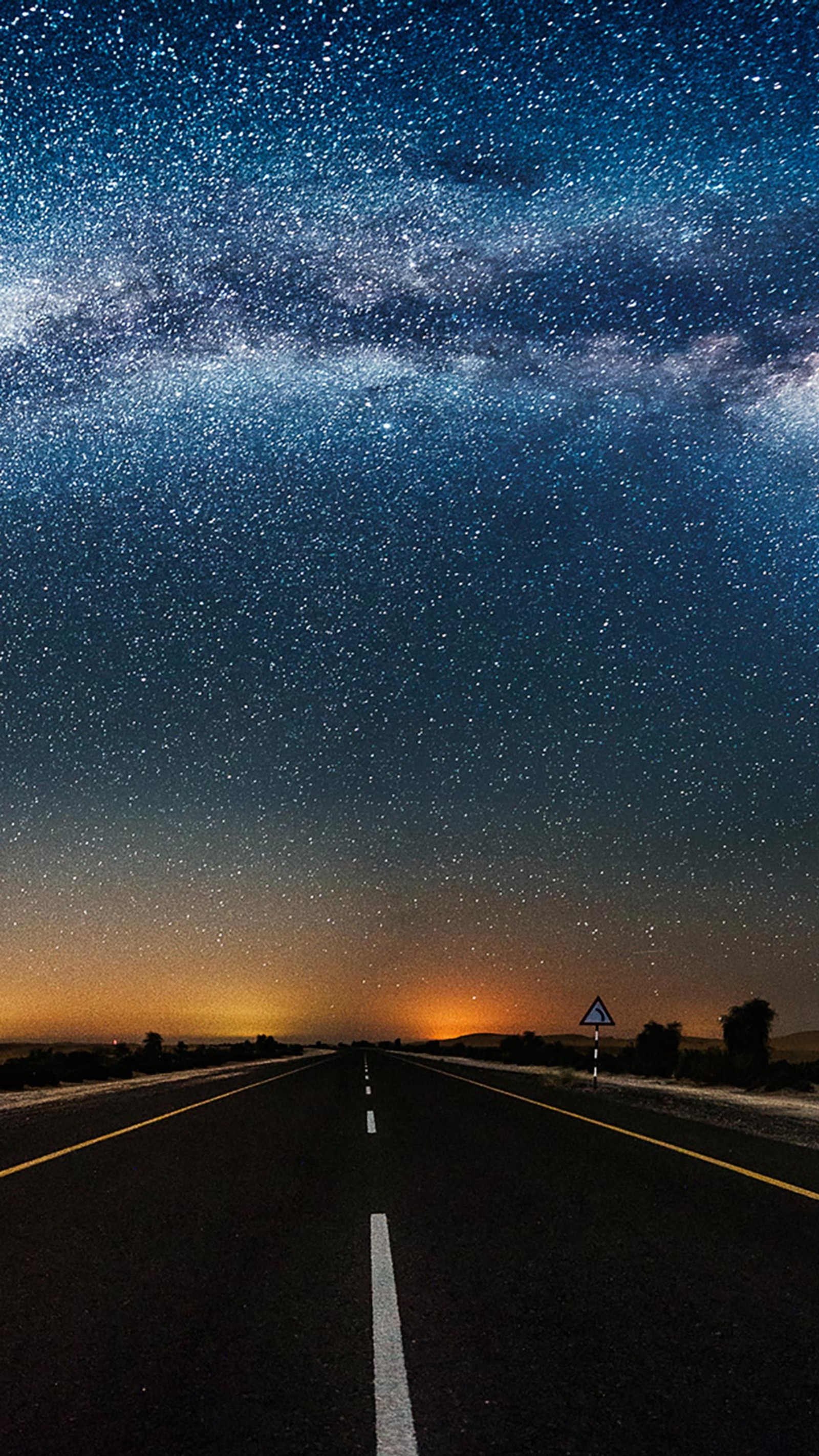 Céu estrelado sobre uma rodovia com uma placa de trânsito (preto, azul, pacífico, estrada, espaço)