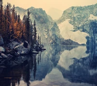 Reflexão de inverno serena em um lago tranquilo entre montanhas cobertas de neve e árvores douradas