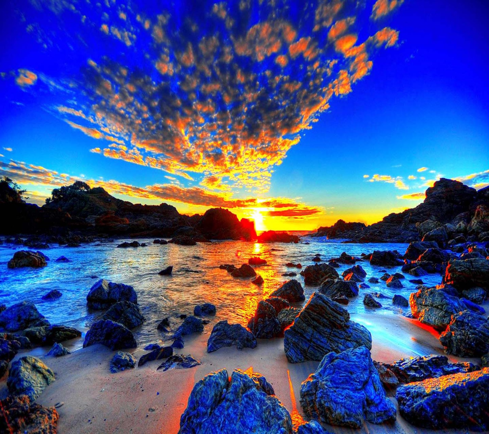 A view of a beach with rocks and water at sunset (good, look)