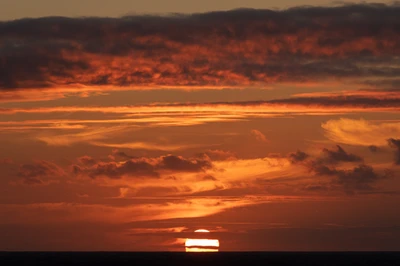 Vibrant Sunset Over the Horizon: A Symphony of Orange and Cumulus Clouds