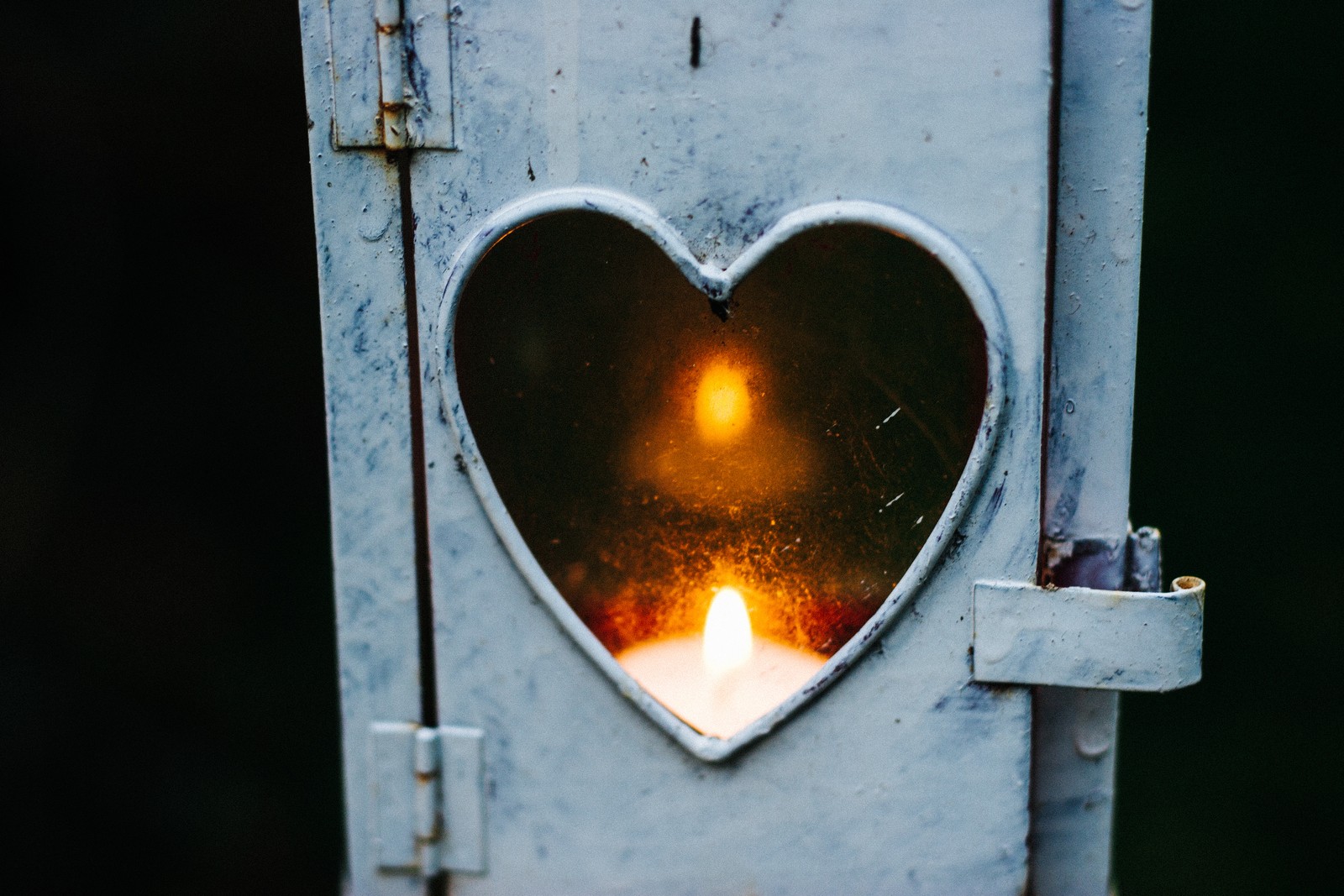 Il y a une bougie en forme de cœur allumée dans la fenêtre (feu, porte, organe, amour, flamme)