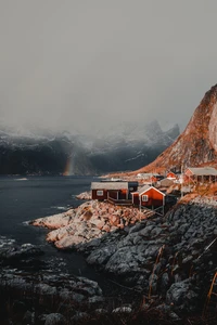 Lofoten-Küste bei Sonnenuntergang: Bunte Bauernhäuser, die sich an majestätische Berge und einen Fjord schmiegen.