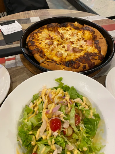 Ensalada vegetariana y pizza inspirada en tailandesa en vajilla