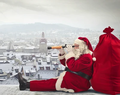 Santa Claus usando un telescopio para observar un paisaje urbano nevado, con un gran saco rojo a su lado.