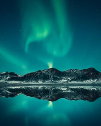 Faszinierende Aurora, die sich über eine ruhige Berglandschaft spiegelt