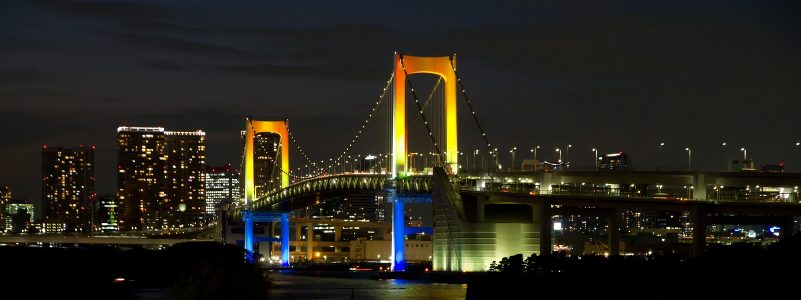 Uma vista de uma ponte com luz colorida em arco-íris sobre ela (ponte arco íris, ponte de manhattan, manhattan bridge, ponte suspensa, ponte)