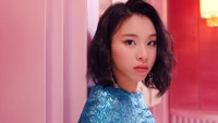 Chaeyoung in einem funkelnden blauen Outfit vor einem pinken Hintergrund