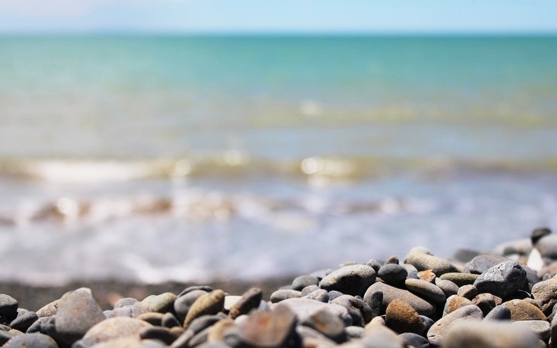 На пляже рядом с водой лежит куча камней (море, побережье, галька, волна, берег)