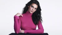 Kendall Jenner in einem auffälligen pinken Rollkragenpullover, der Eleganz und Selbstbewusstsein ausstrahlt.