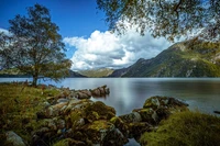 Lago sereno nas montanhas com águas refletivas e costa rochosa