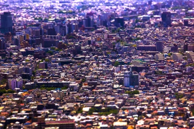 A vibrant birds-eye view of an expansive urban landscape, showcasing a densely populated cityscape with a mix of residential and commercial areas, framed by distant horizons.