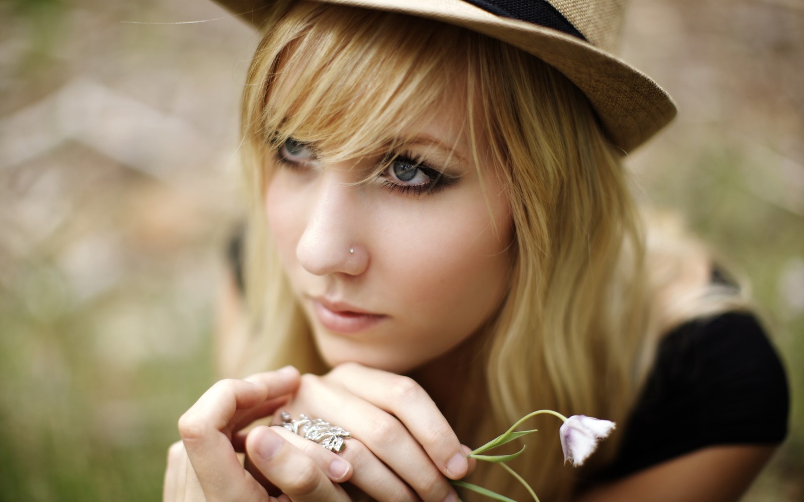 Femme blonde avec un chapeau et une bague tenant une fleur (gris, cheveux, blond, beauté, cheveux longs)