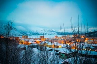 Aldeia montanhosa coberta de neve ao crepúsculo com reflexão serena na água