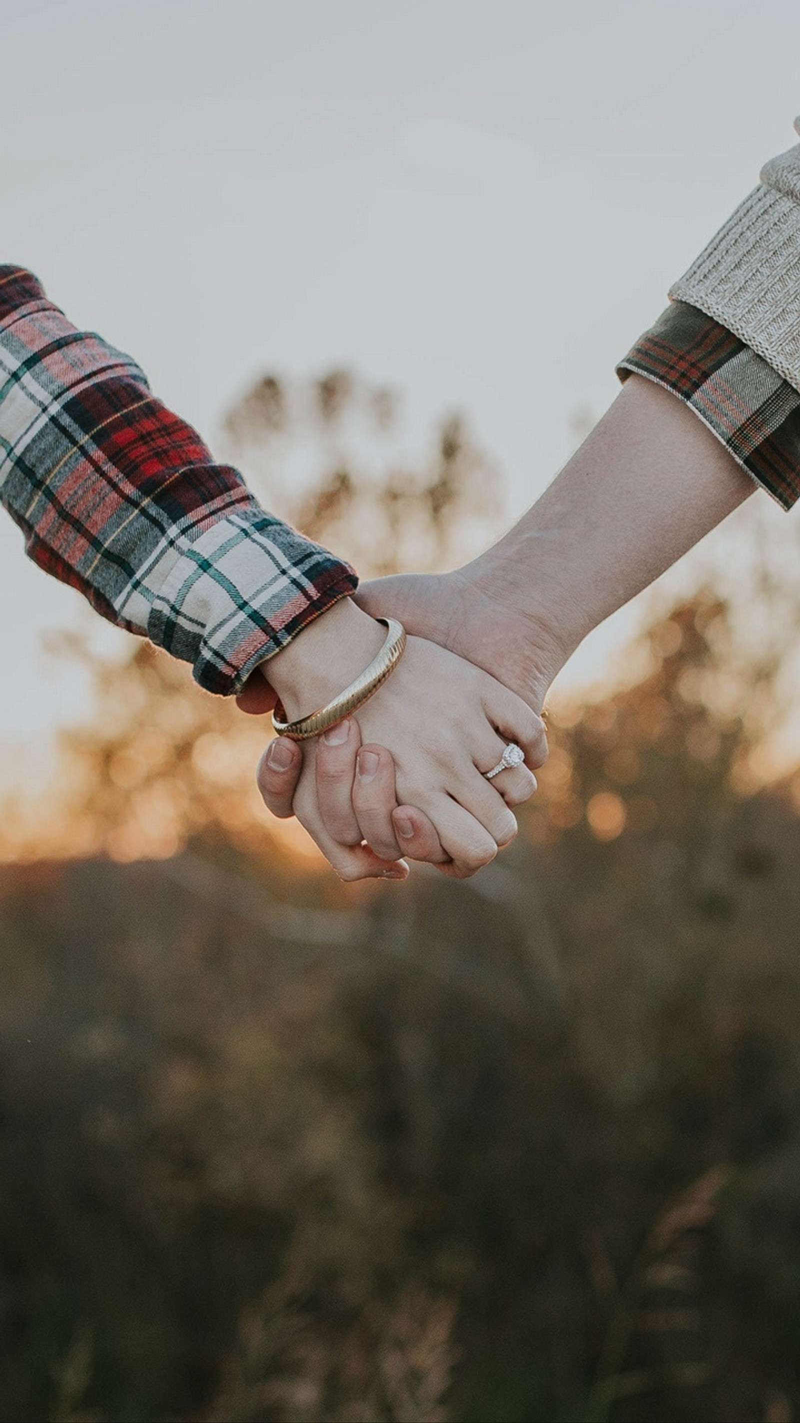 Zwei menschen halten sich auf einem feld die hände (paar, paare, hand, liebe, beziehung)