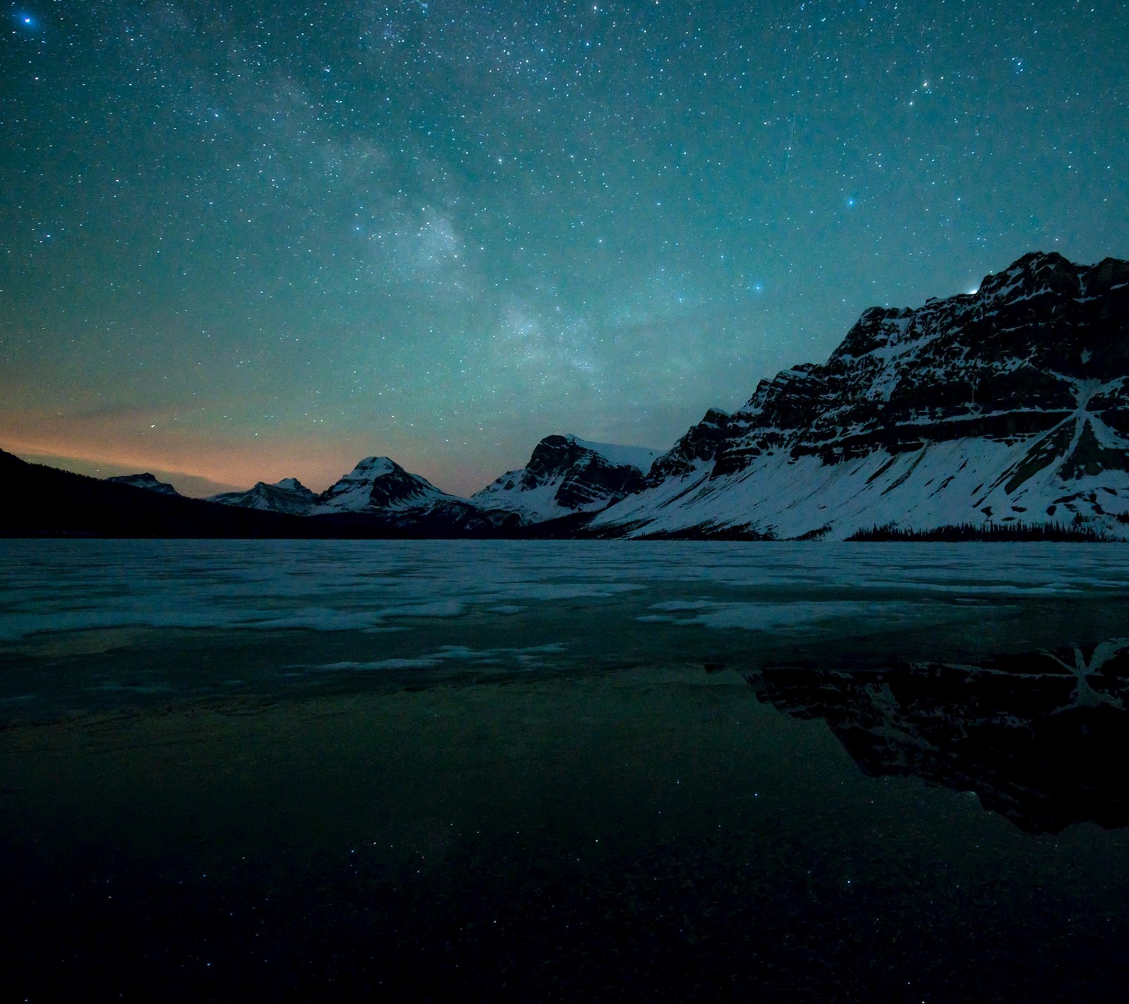 A view of a lake with a mountain in the background (nature, night, stars)