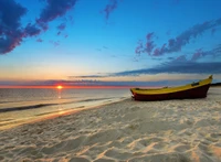 Sonnenuntergang über einem ruhigen Strand mit einem gelben Boot