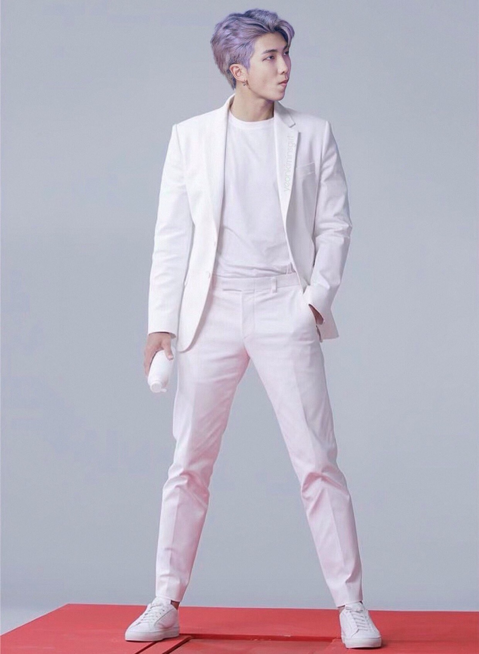 Un homme en costume blanc et baskets blanches se tient sur un tapis rouge (bts, namjoon)