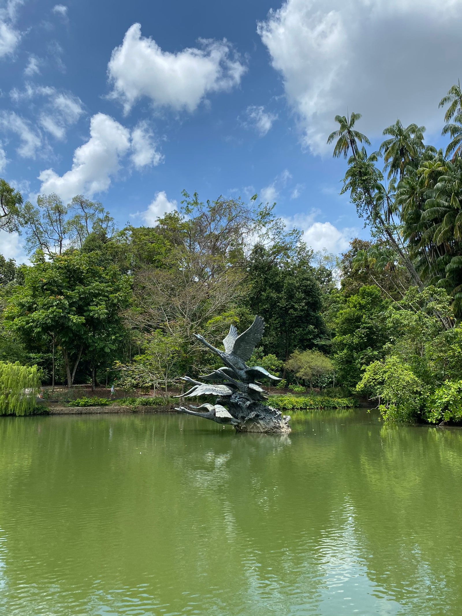 Há uma estátua de um pássaro voando sobre um lago (natureza, vegetação, nuvem, recursos hídricos, paisagem natural)