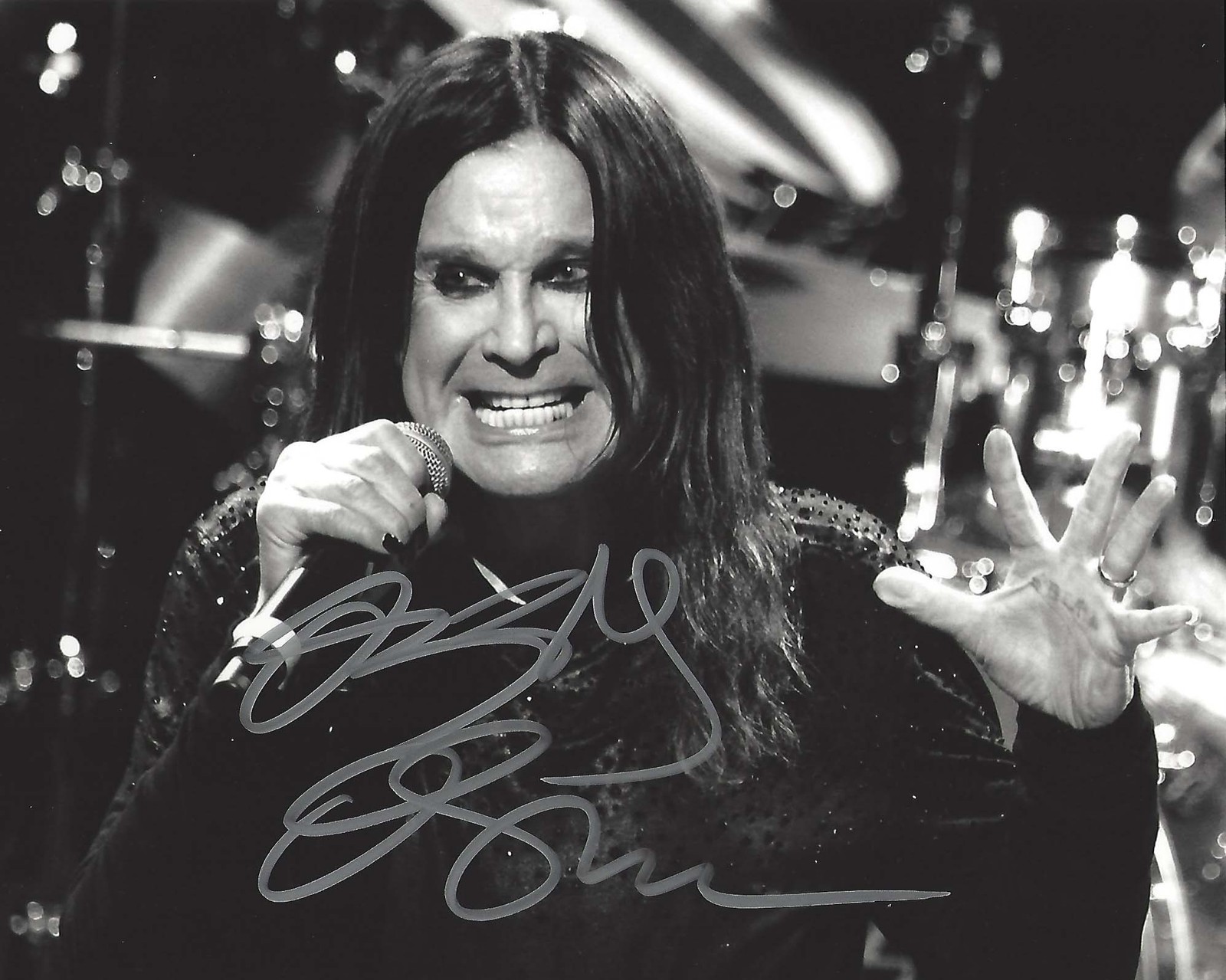 Una foto panorámica de un hombre con cabello largo y un micrófono (ozzy osbourne, black sabbath, heavy metal, monocromo, música pop)