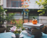 Cantinho de leitura aconchegante com livros, uma laranja fresca e acentos florais