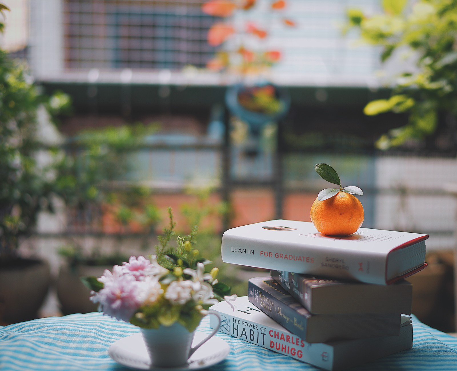 Il y a une pile de livres sur une table avec une orange sur le dessus (livre, lecture, table, orange, chambre)